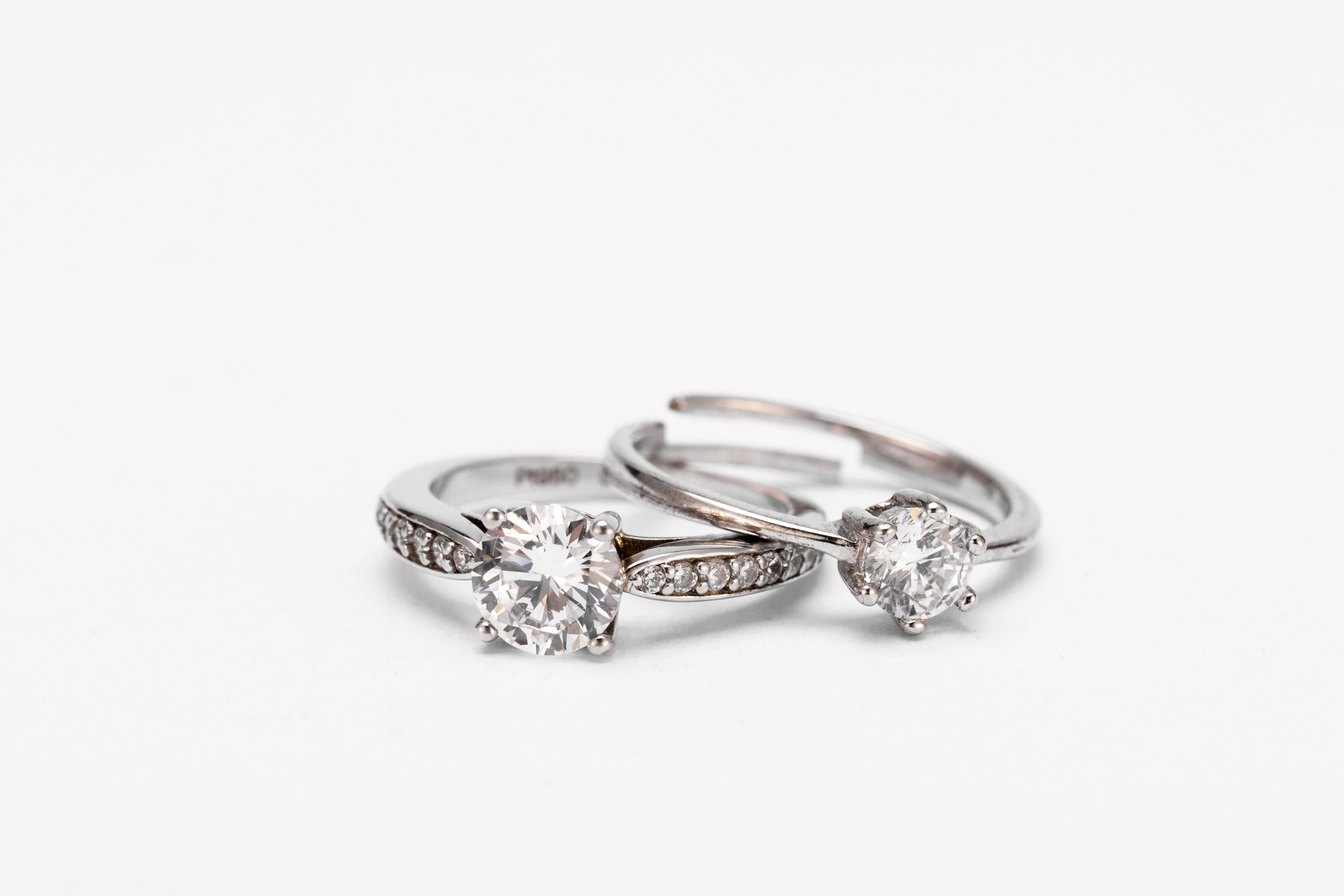 closeup-shot-two-diamond-rings-white-surface.jpg